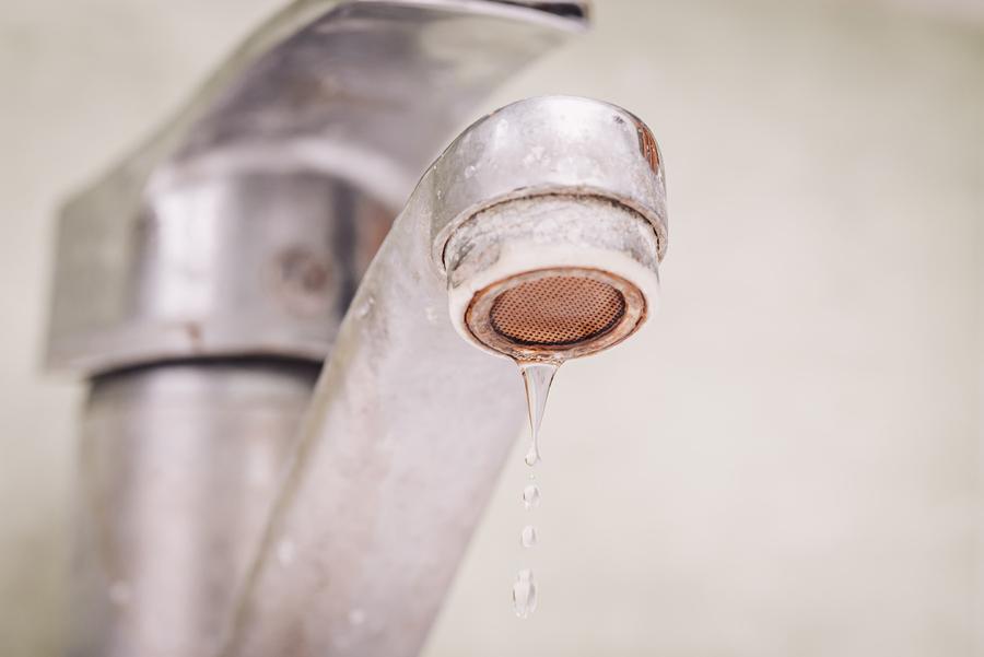 Water dripping from tap covered in limestone because of hard water